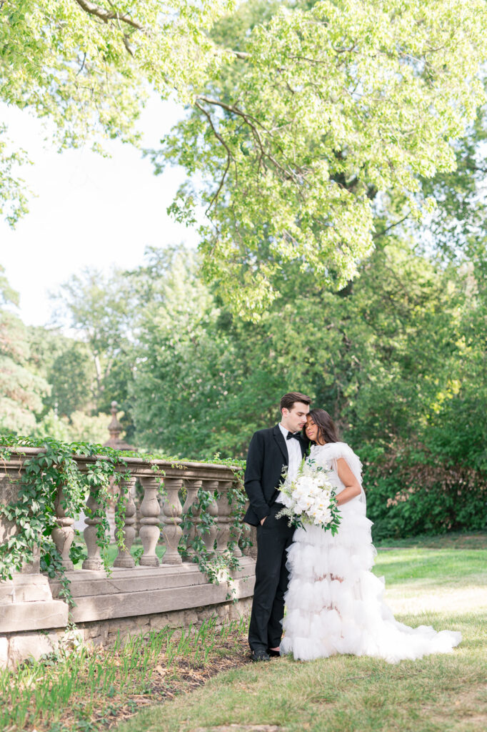couple leading on each other by a stone baluster railing