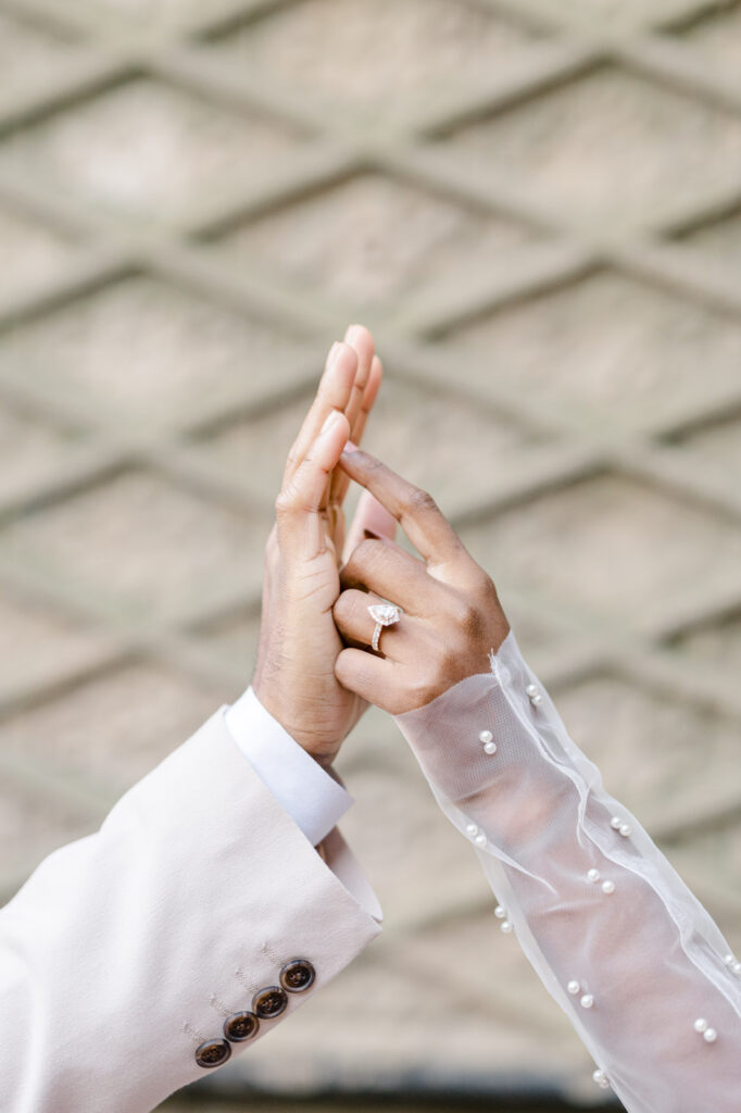 detail photo of a couple's hands delicately touching each other featuring an engagement ring