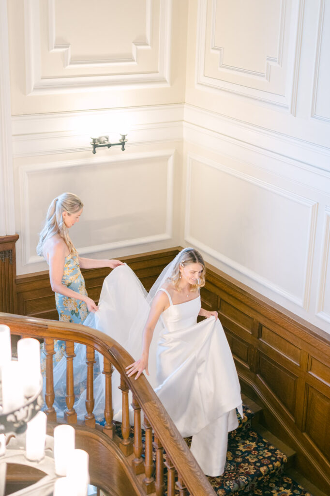 bridemaid helping bride down the stairs