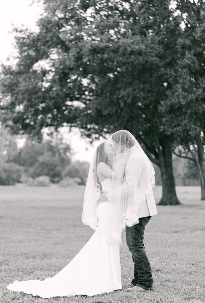 couple sharing a kiss under the veil at the willowynn barn in houston